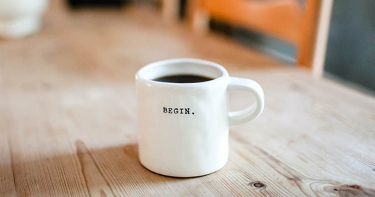 Full coffee cup on table with 'begin' written on the side