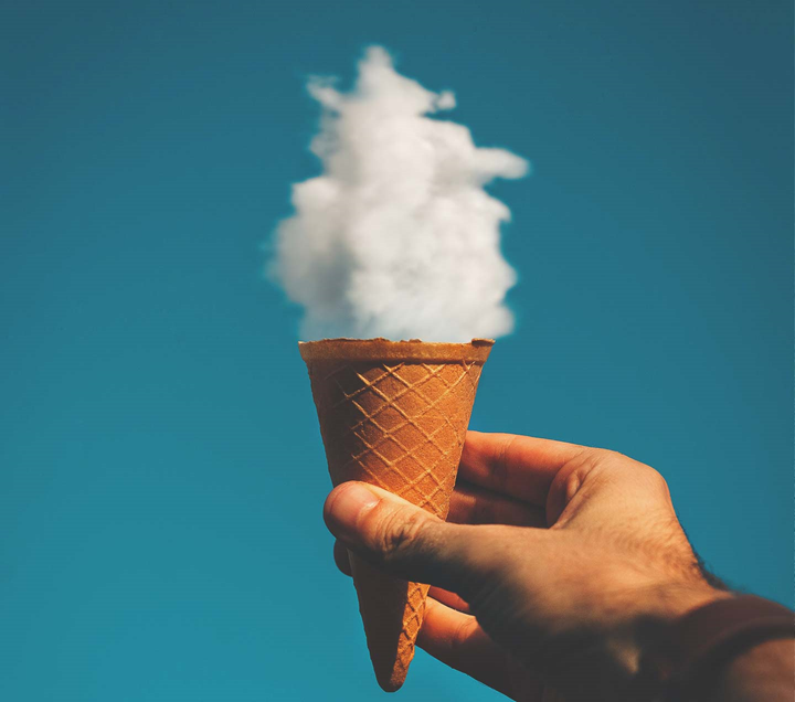 Hand holding an ice cream cone with a cloud in it