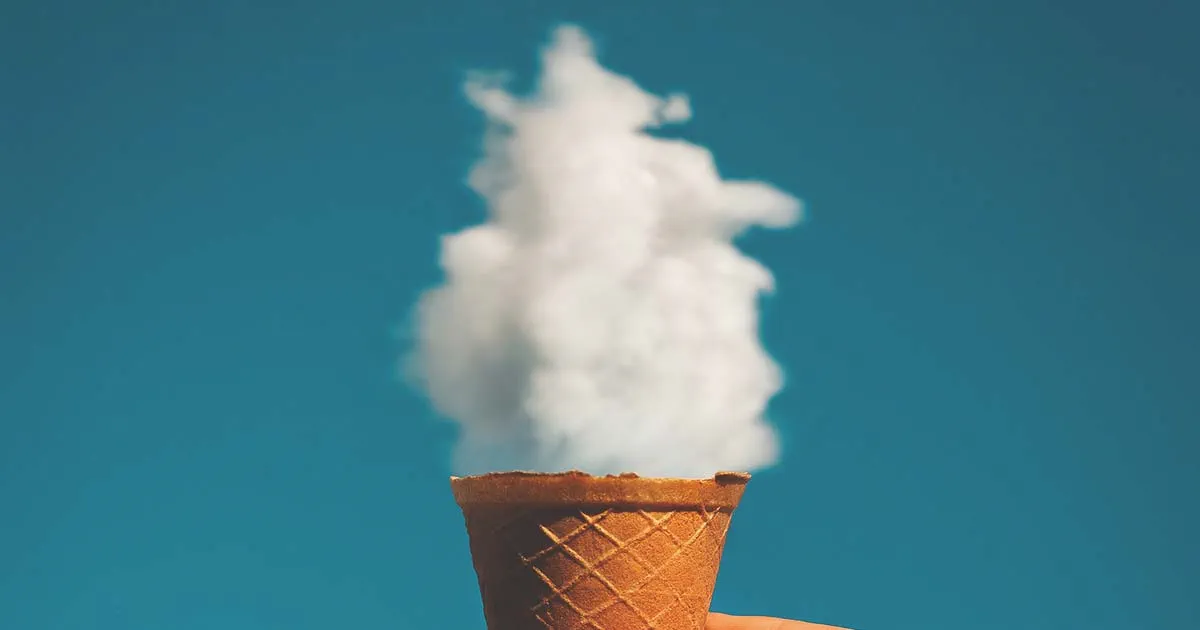 Hand holding an ice cream cone with a cloud in it