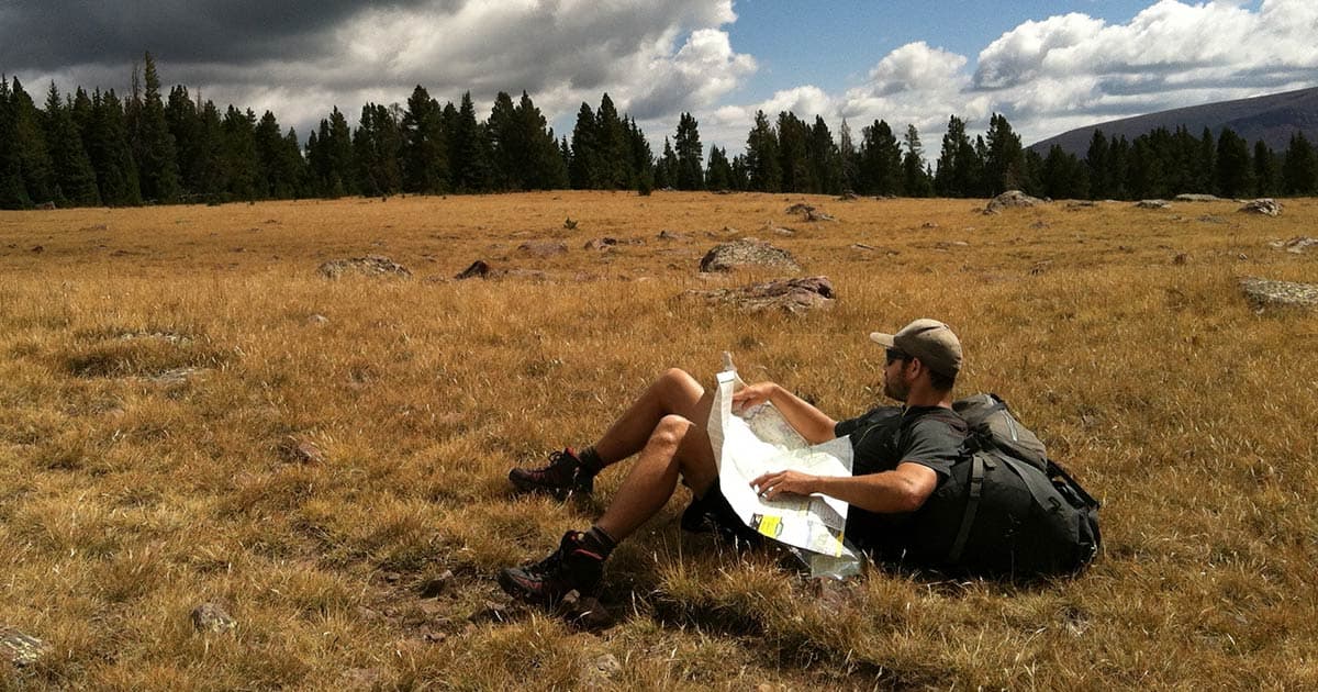 Hiker in a field reading a map