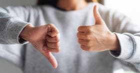 Woman making thumbs up and thumbs down representing positive or negative feedback